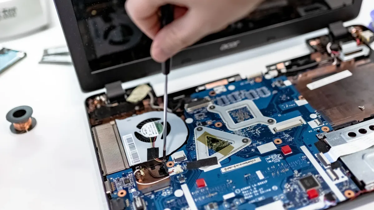 Dłoń ze śrubokrętem przy płycie głównej laptopa — Jak zamówić odbiór laptopa Lenovo do naprawy