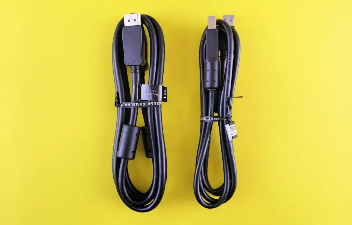Dwa kable (DisplayPort i USB) leżące obok siebie na żółtym tle — brak sygnału na złączu USB-C / DisplayPort laptopa