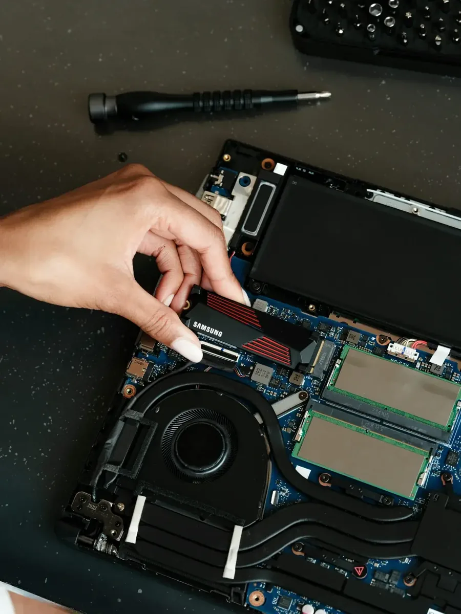 Dłoń montująca dysk SSD Samsung z radiatorem do laptopa obok pamięci RAM — dysk laptopa wydaje dziwne dźwięki — pierwsza pomoc