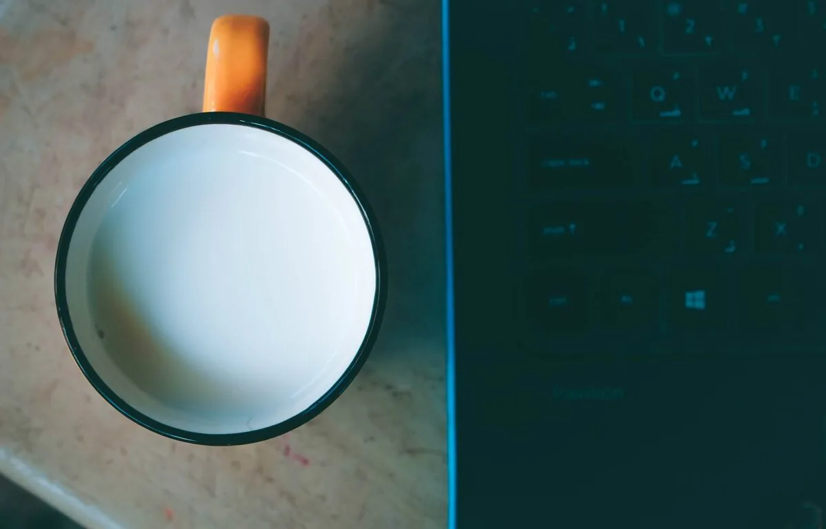 Kubek z mlekiem stojący tuż obok otwartego laptopa z klawiaturą — zwarcia punktowe po zalaniu — jak je lokalizujemy